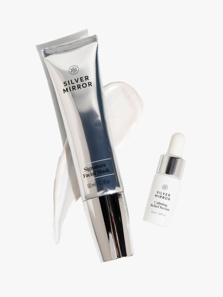 A silver tube of Silver Mirror Skincare Signature Facial Mask and white dropper vial of Calming Relief Serum on a light gray background